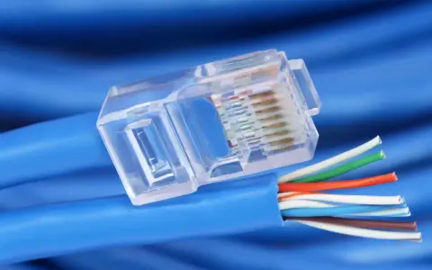 Gros plan sur un connecteur transparent de câble réseau RJ45, révélant les fils colorés prêts pour un débit de câble RJ45 optimal.