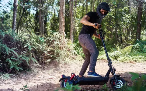 Un homme en casque roule en trottinette électrique dans une forêt. Il semble rencontrer un problème, peut-être un code erreur e8 trottinette électrique.