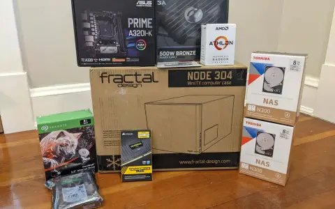 Composants pour installer un NAS : carte mère ASUS, processeur AMD Athlon, boîtier Fractal Design, alimentation, RAM Corsair, et deux disques durs Toshiba 8 To.