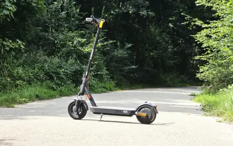 Trottinette Xiaomi grise sur une route asphaltée, entourée de verdure. Parfait pour explorer la nature et profiter de son autonomie.