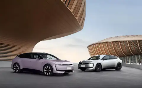 Deux Audi E5 Sportback, une lilas et une argentée, se présentent devant des bâtiments aux formes organiques.