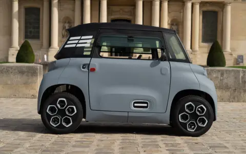 Une petite voiture grise, un ami pour la ville, se gare devant un bâtiment imposant.