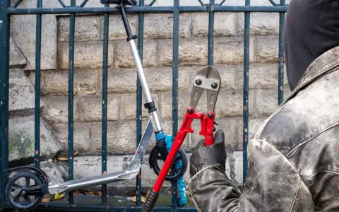 Un voleur, cagoulé et ganté, s'apprête à couper le cadenas d'une trottinette volée avec une pince monstre. Comment retrouver une trottinette volée ?