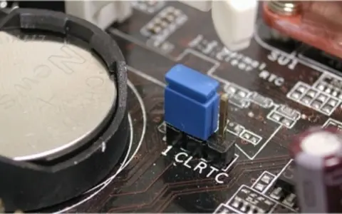 Gros plan sur une carte mère, montrant la pile bouton et le cavalier CLRTC pour réinitialiser le CMOS.