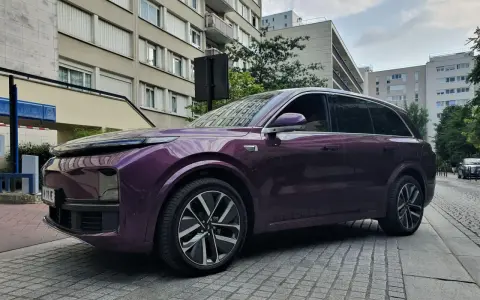 Une élégante li auto violette se gare devant des immeubles résidentiels.