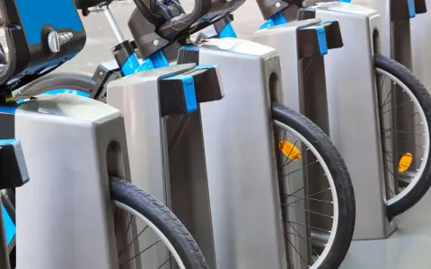 Des vélos bleus et gris sont rangés, prêts à recharger sur une borne auto.