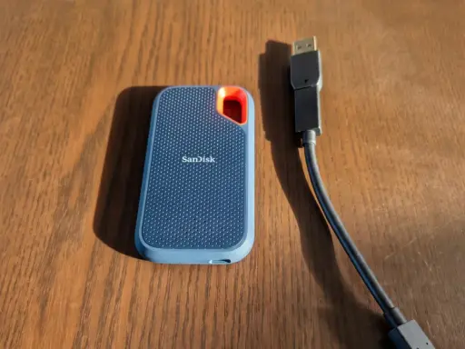 Disque dur externe SanDisk, un SSD portable bleu avec un câble USB.