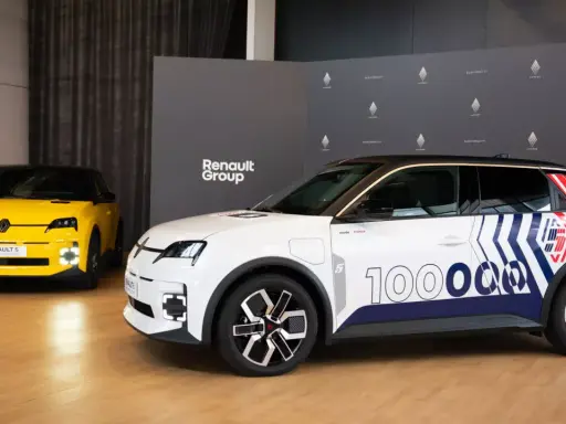 Deux Renault 5 électriques, une jaune et une blanche décorée pour un essai, présentées devant le logo Renault Group.