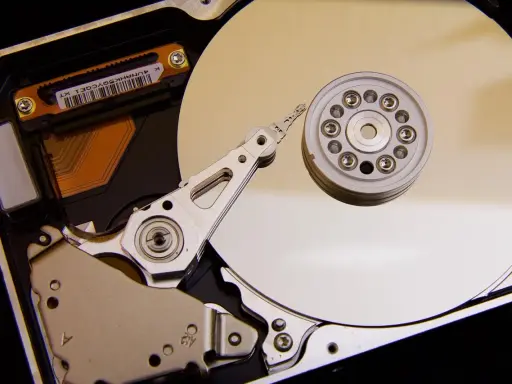 Vue rapprochée de l'intérieur d'un disque dur de PC, montrant le plateau, la tête de lecture/écriture et le moteur. L'emplacement du disque dur est essentiel pour le stockage des données.