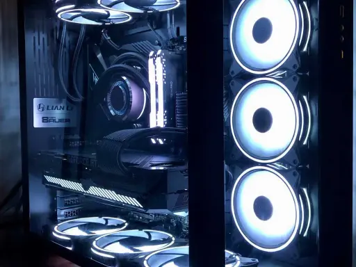 Intérieur d'un PC gamer avec éclairage RGB. On distingue la carte graphique, la carte mère, le système de refroidissement liquide et plusieurs ventilateurs. L'alimentation PC est bien visible.