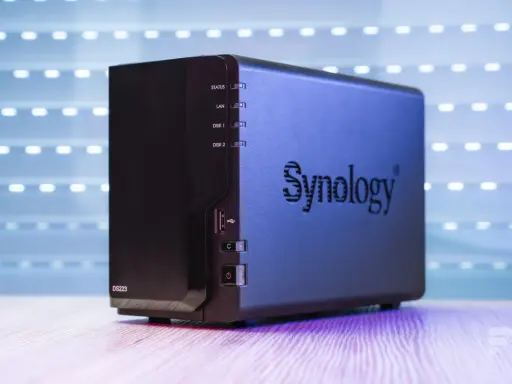 Un appareil Synology DS223, un nas stockage compact, est présenté sur un bureau en bois, avec un fond lumineux.