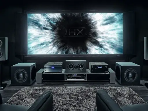 Installation home cinema avec écran THX, amplificateur, enceintes et fauteuils en cuir noir pour une expérience immersive.