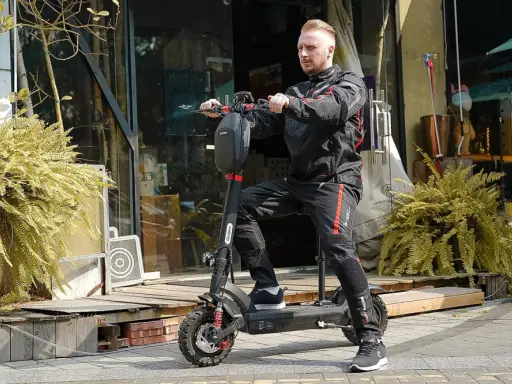 Un homme en tenue de moto est prêt pour un trajet de 10 km en trottinette électrique. Le temps est parfait pour explorer la ville.