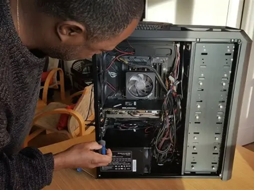 Un homme ajuste l'alimentation d'un PC. Il manipule un tournevis pour le sens alimentation pc.