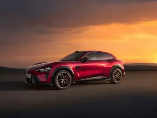 Le SUV rouge Xiaomi Yu7, aux lignes futuristes, se dresse sur un tarmac sous un ciel orangé spectaculaire.
