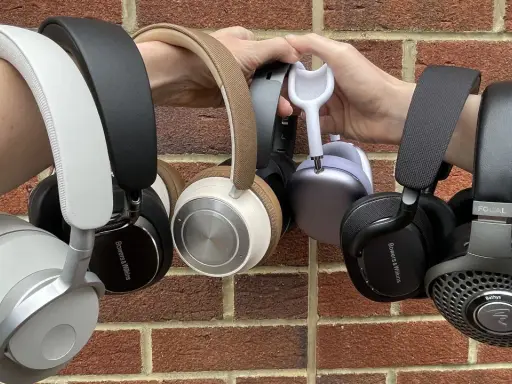 Collection de casques supra-auriculaires, certains tenus par des mains, sur fond de mur de briques.