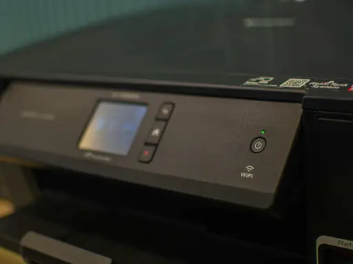 Panneau de contrôle d'une imprimante avec écran, boutons et indicateur Wi-Fi. Une caractéristique imprimante notable est sa connectivité sans fil.