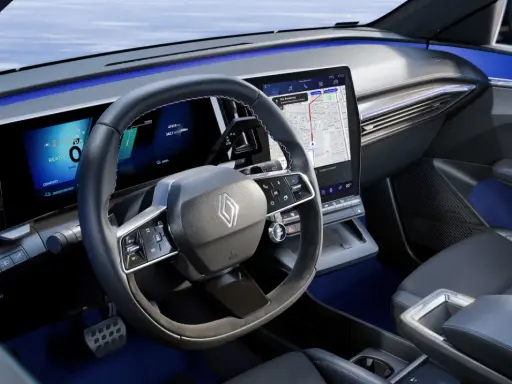 Tableau de bord moderne de la future Renault Mégane, avec écrans numériques, volant multifonction et éclairage d'ambiance bleu.