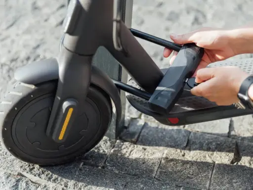 Mains tenant une clé pour comment attacher sa trottinette électrique. Le cadenas est fixé au cadre.