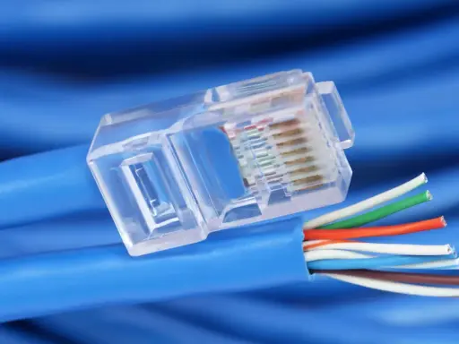Gros plan sur un connecteur transparent de câble réseau RJ45, révélant les fils colorés prêts pour un débit de câble RJ45 optimal.