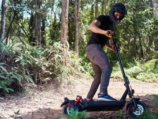 Un homme en casque roule en trottinette électrique dans une forêt. Il semble rencontrer un problème, peut-être un code erreur e8 trottinette électrique.