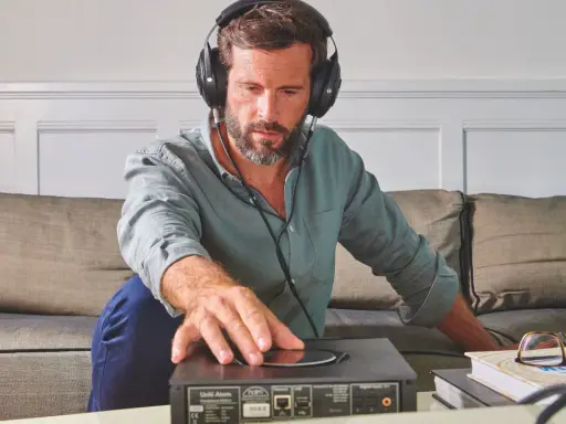 Homme avec casque audio, ajustant un appareil audio. L'impédance du casque audio est cruciale pour une écoute optimale.