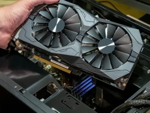 Main d'homme tenant une carte graphique double ventilateur. Pour savoir si une carte graphique est morte, vérifiez les artefacts visuels ou l'absence de signal.