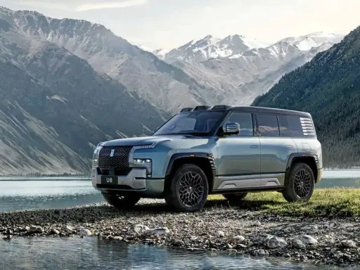 Le byd yangwang u8, un SUV imposant, se tient au bord d'un lac, avec des montagnes enneigées en arrière-plan.