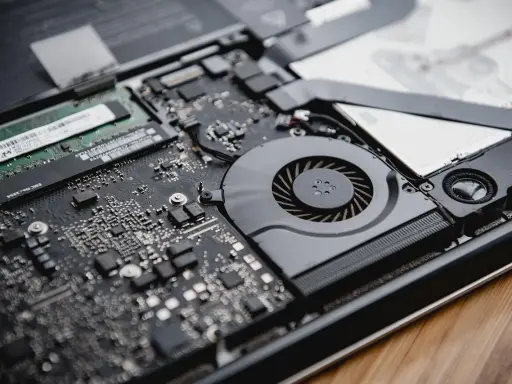 Intérieur d'un ordinateur portable ouvert, montrant la carte mère, le ventilateur et la RAM. La RAM est essentielle pour la définition de la performance.