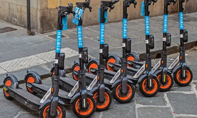 Une rangée de trottinettes électriques Helbiz, prêtes à l'emploi. Imaginez pouvoir debrider trottinette pour une balade urbaine !