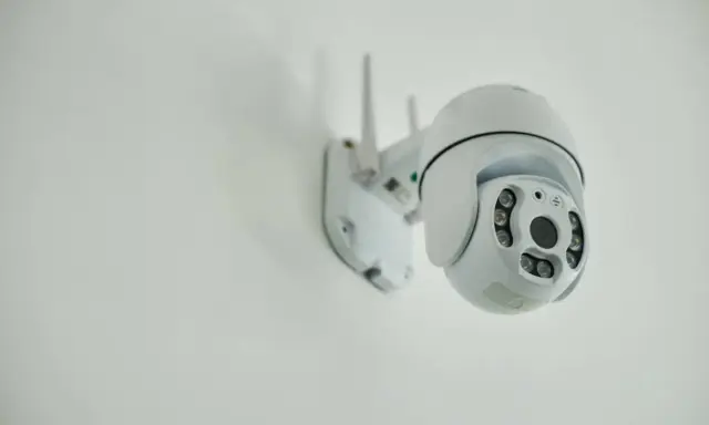 Installation d'une caméra IP blanche sur un mur. Elle est orientable et dotée de plusieurs LED infrarouges.