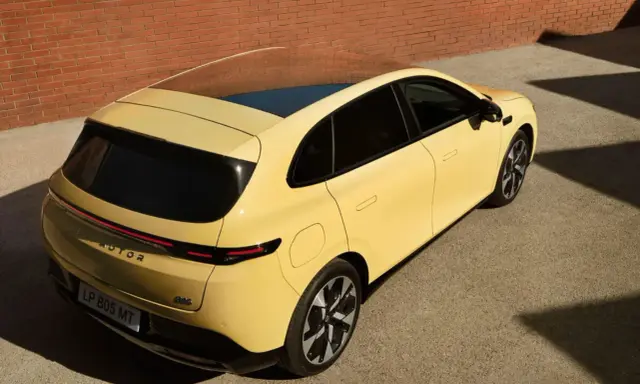 Le Leapmotor B05, un SUV jaune vif, se gare près d'un mur de briques.
