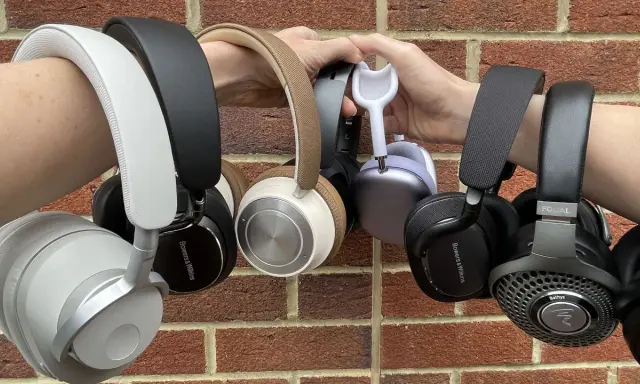 Collection de casques supra-auriculaires, certains tenus par des mains, sur fond de mur de briques.