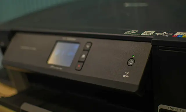 Panneau de contrôle d'une imprimante avec écran, boutons et indicateur Wi-Fi. Une caractéristique imprimante notable est sa connectivité sans fil.