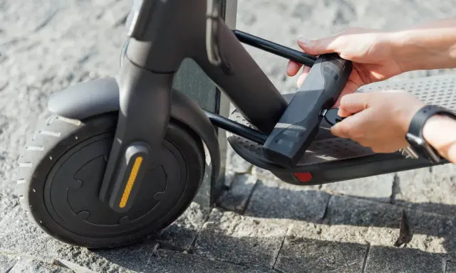 Mains tenant une clé pour comment attacher sa trottinette électrique. Le cadenas est fixé au cadre.