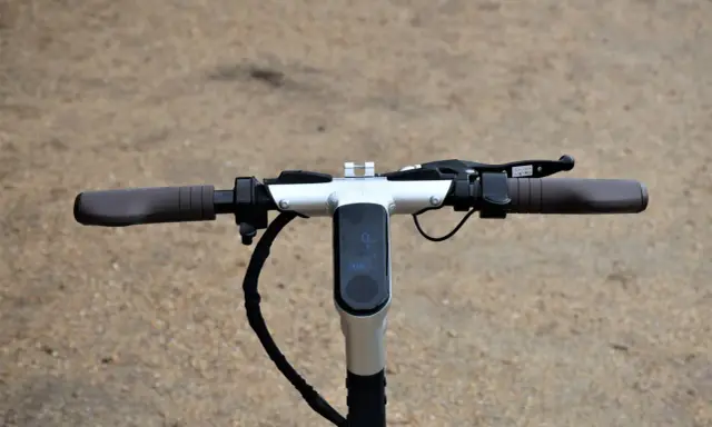 Guidon d'une trottinette électrique, avec écran digital affichant la vitesse et l'autonomie. La hauteur du guidon est idéale pour une conduite confortable.