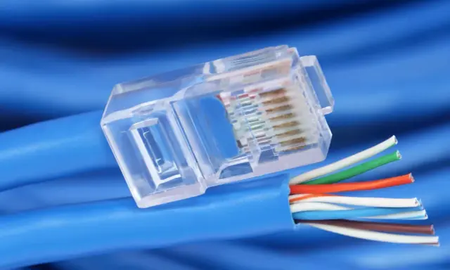 Gros plan sur un connecteur transparent de câble réseau RJ45, révélant les fils colorés prêts pour un débit de câble RJ45 optimal.