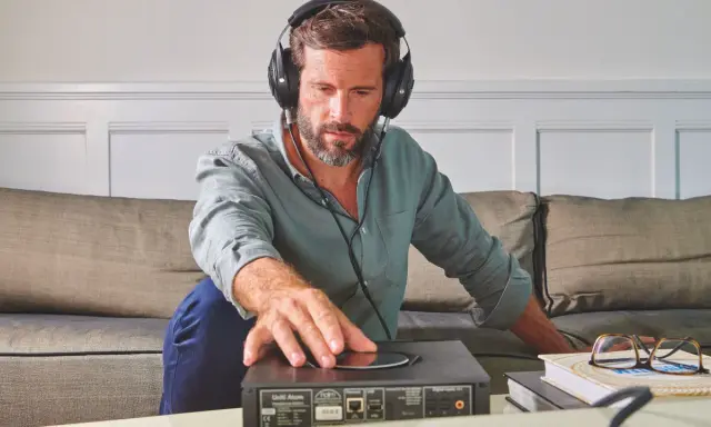Homme avec casque audio, ajustant un appareil audio. L'impédance du casque audio est cruciale pour une écoute optimale.
