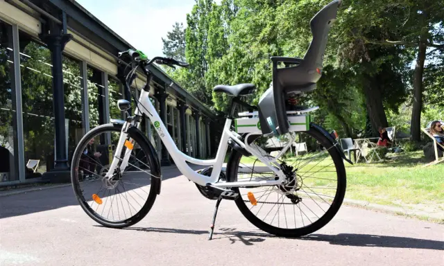 Vélo blanc avec siège enfant, prêt à rouler. Peut-on rouler avec un vélo électrique sans batterie ? Oui, mais ce sera plus difficile !