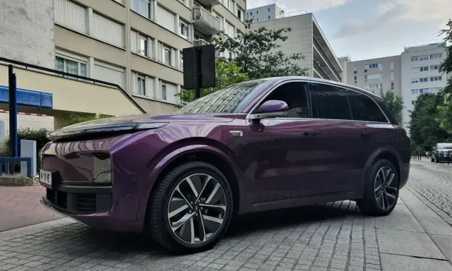 Une élégante li auto violette se gare devant des immeubles résidentiels.