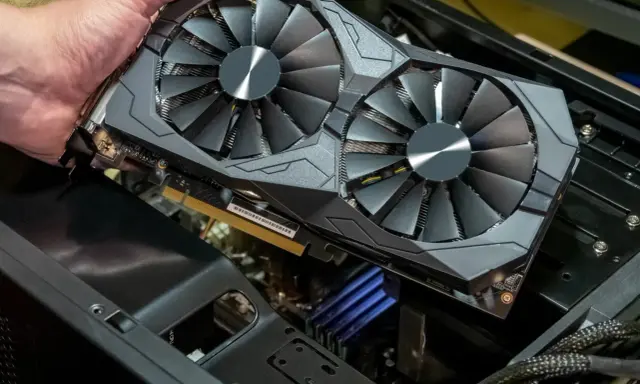 Main d'homme tenant une carte graphique double ventilateur. Pour savoir si une carte graphique est morte, vérifiez les artefacts visuels ou l'absence de signal.