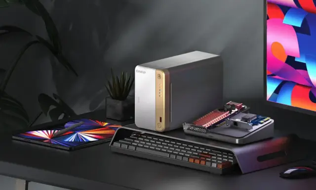 Un bureau moderne avec un NAS QNAP, une tablette, un clavier et un écran coloré. Idéal pour choisir son NAS et organiser ses données.