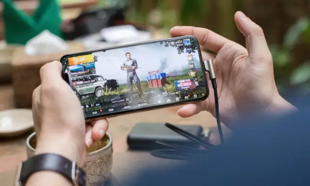 Main d'une personne tenant un smartphone affichant un jeu vidéo, parfait pour les jeux sans connexion.