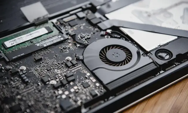 Intérieur d'un ordinateur portable ouvert, montrant la carte mère, le ventilateur et la RAM. La RAM est essentielle pour la définition de la performance.