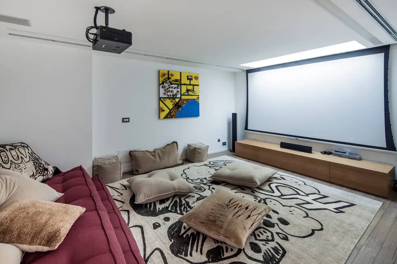 Salle de cinéma maison avec vidéoprojecteur au plafond, écran géant, canapé confortable et tapis graphique. Idéal pour savoir comment choisir un vidéoprojecteur.
