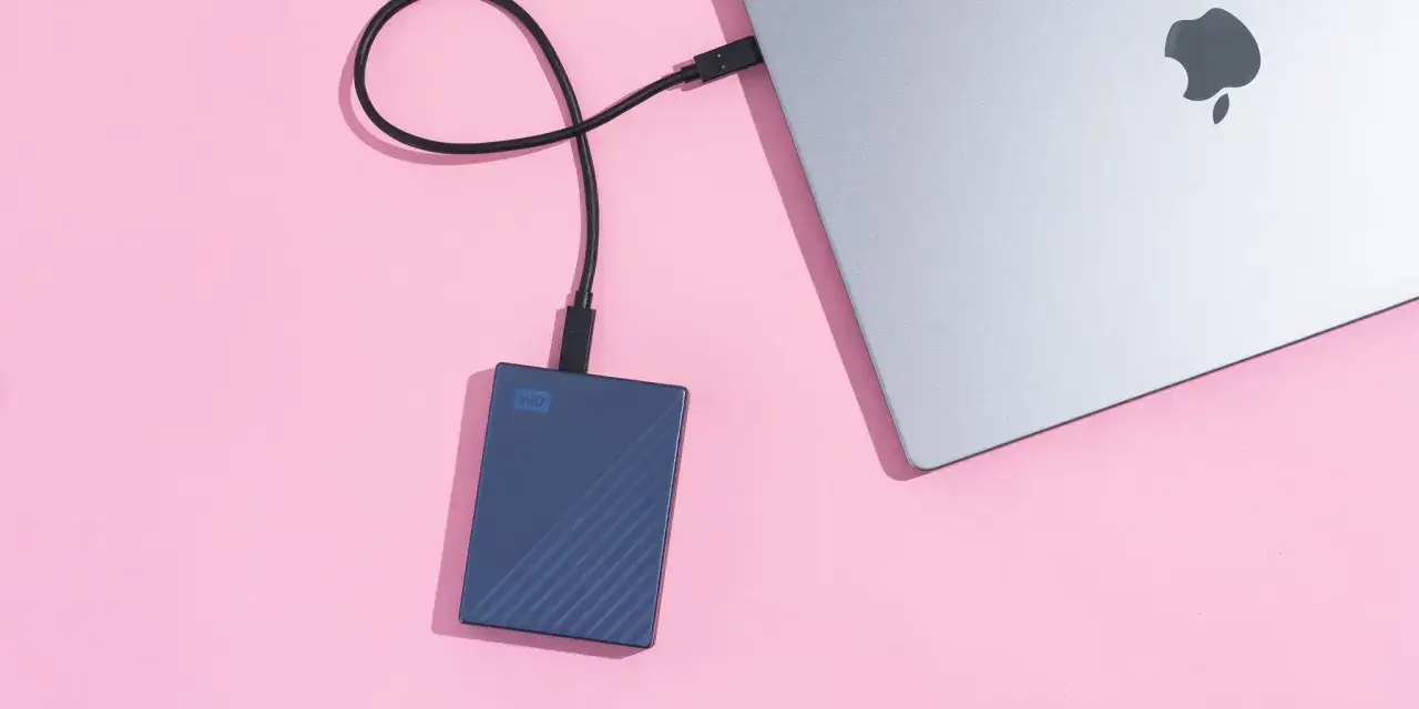 Disque bleu connecté à un MacBook pour une sauvegarde externe.