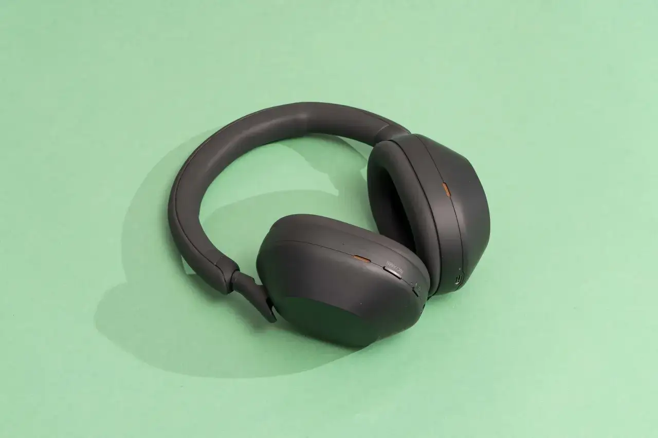 Casque circum-aural noir, pos&eacute; sur fond vert menthe. Id&eacute;al pour une immersion sonore totale.