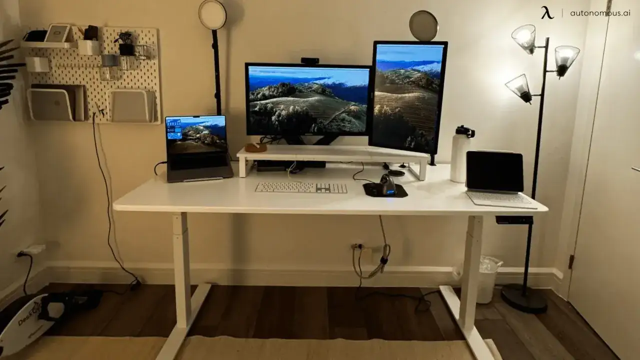 Bureau moderne avec deux écrans, un ordinateur portable et une tablette. Le choix entre 27 pouces vs 32 pouces pour les moniteurs est crucial pour l'espace de travail.